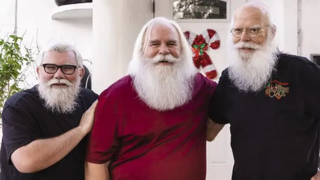 Tres intérpretes de Santa posan al frente de una casa en Miami