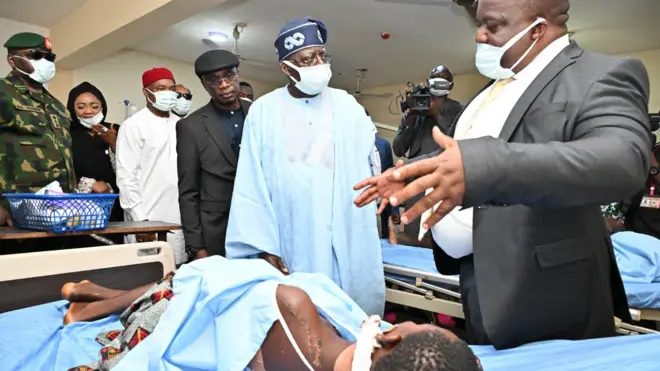Nigeria President Bola Tinubu wear sky blue cloth and Navy blue cap, e astand opposite man wey wear back suit we be like say e dey explain something to am as e visit victims of di Benue killings for Hospital 