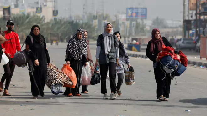 Palestinians fleeing north Gaza, carry bags as they walk towards the south