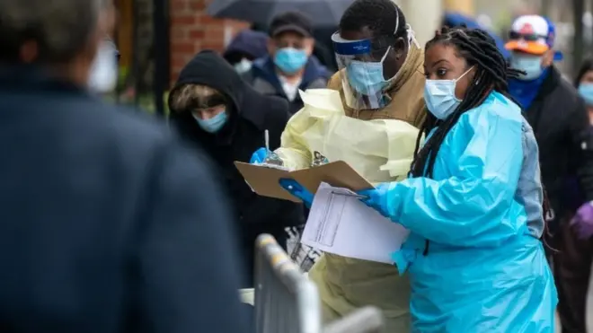 Medical workers assist people standing in line at NYC Health + Hospitals/Gotham Health, Gouverneur waiting to be tested for the coronavirus (COVID-19) on April 24, 2020, in New York City.