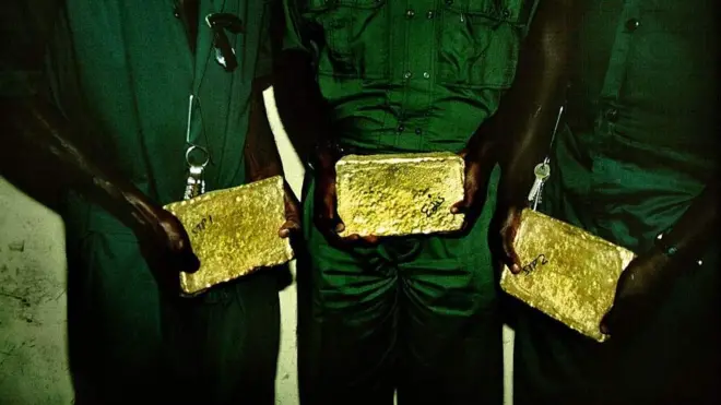 3 men hold gold bar for hand