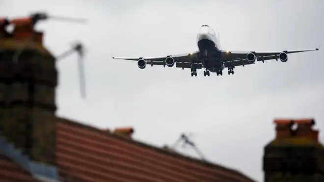 Avião sobrevoando casas