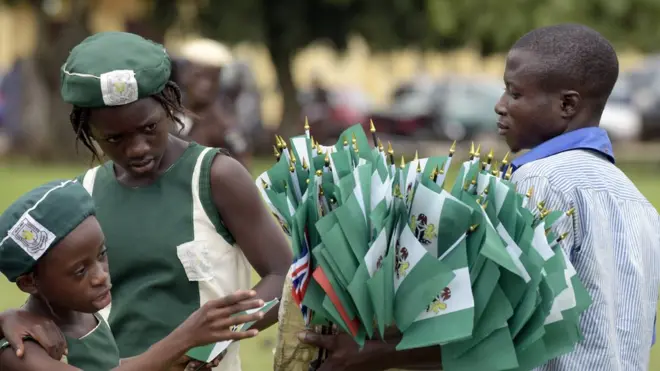 Ọmode kunrin kan n ko asia orileede Naijiria lọwọ lọjọ ayajọ òṣèlú tiwá n tiwá