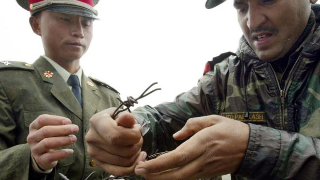 This file photo taken on July 5, 2006 shows a Chinese soldier (L) and Indian soldier placing a barbed wire fence following a meeting of military representatives at the Nathu La border crossing between India and China in India"s northeastern Sikkim state. A border standoff between Chinese and Indian troops on a remote Himalayan plateau has heightened long-standing tensions while ensnaring a tiny kingdom, Bhutan, between the two nuclear-armed powers.