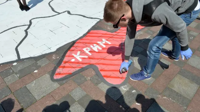 Чоловік малює карту України, виділяючи Крим червоним кольором