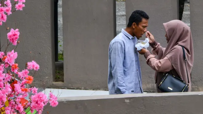 印尼班达亚齐2004年海啸纪念馆外一名包着头巾的穆斯林妇女给一位男士喂食（11/3/2020）