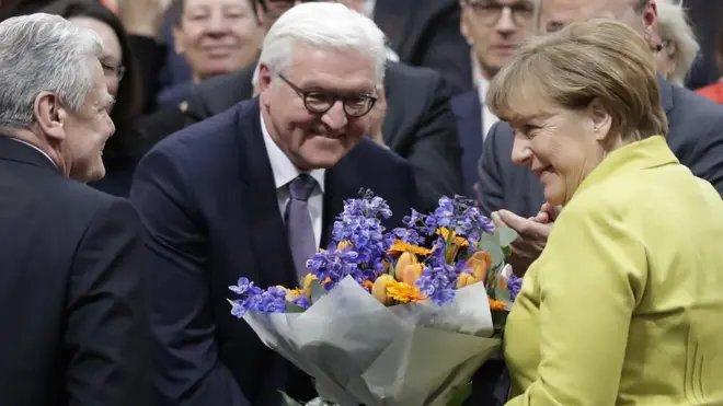 นางแมร์เคิล (ซ้าย) กับนายเก๊าค์ (ขวา) แสดงความยินดีกับนายชไตน์ไมเออร์ (กลาง)