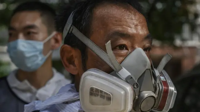 Para anggota Blue Sky Rescue memakai APD sebelum menyemprotkan cairan disinfektan kawaan permukiman di Beijing, 21 Juni.