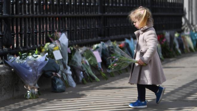 A young girl holds flowers outside Buckingham Palace on 9 April 2021