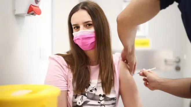 A person receives a dose of the Pfizer BioNTech vaccine at the Central Middlesex Hospital in London, Britain, August 1, 2021.