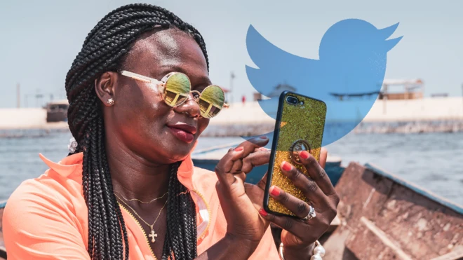 Une femme au Ghana utilisant un téléphone avec le logo Twitter en arrière-plan