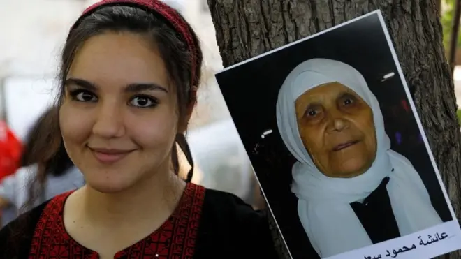 Seorang perempuan Arab Israel berpose di sebelah foto warga Palestina yang berasal dari kampung Arab di Kfar Hattin yang telah dikosongkan dalam suatu pertemuan pada 15 April 2021 di kampung tersebut untuk menuntut hak pemulangan pengungsi Palestina yang keluar atau diusir dari rumah mereka pada perang 1948 yang diikuti dengan pembentukan negara Israel.