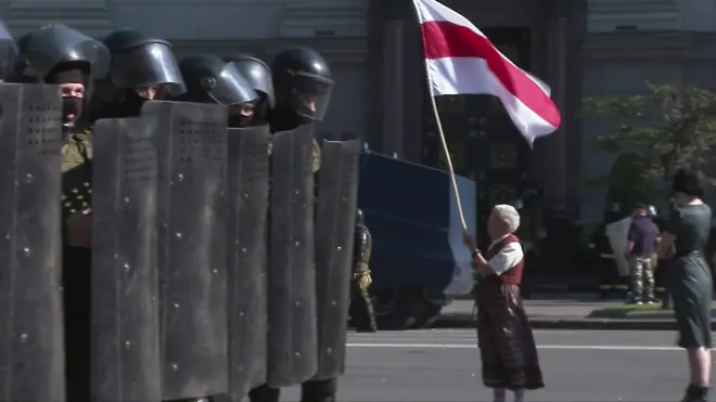 尼娜·巴金斯卡婭（Nina Bahinskaya）举着白俄老国旗站在防暴警察防线前（8/2020）