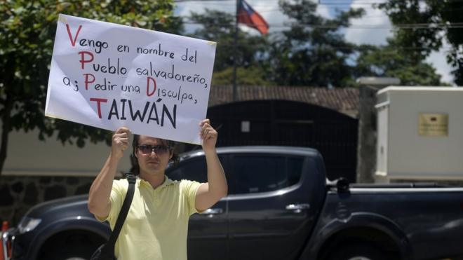 A man holds a placard reading 'Taiwan, in the Name of the Salvadorean People, I Come to Ask For Forgiveness' in front of the embassy of Taiwan in San Salvador on August 21, 2018