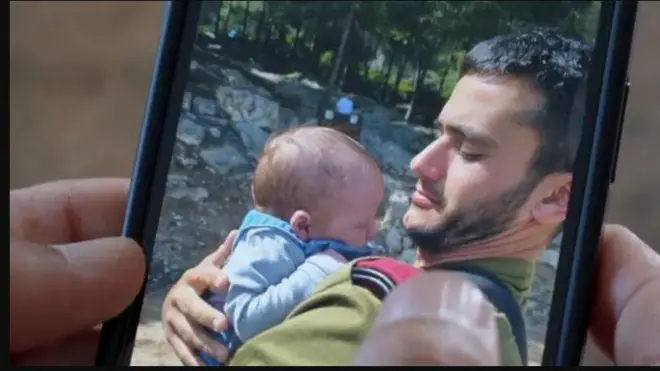 O ku ọjọ diẹ ti Reef yoo ku soju ogun lo ya fọto pẹlu ọmọ tuntun yii, baba rẹ lo n wo fọto naa lori foonu to mu dani yii.