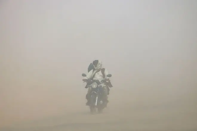 یک مرد موتور سوار در طوفان گرد و خاک