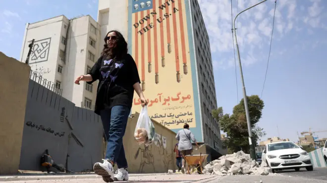 امرأة إيرانية تمر أمام جدارية مناهضة للولايات المتحدة في طهران، إيران، في 17 أغسطس/آب 2026.