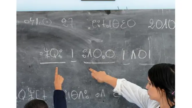 Un enseignant aide un élève à lire un texte en amazigh en 2010.