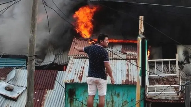 Un hombre mira como el fuego consume parte del Mercado Oriental.