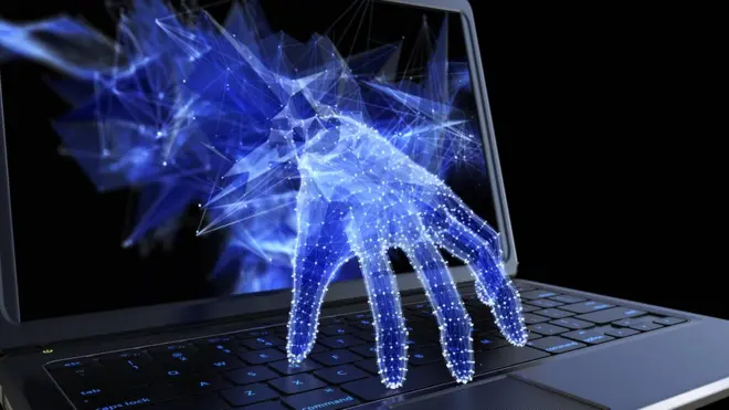 A hand reaching through a computer screen