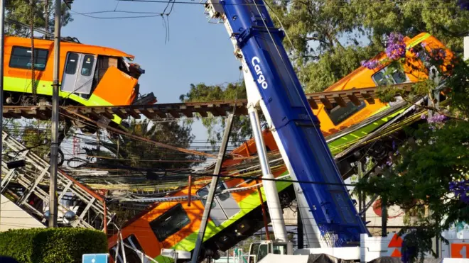 Una grúa frente a dos carros descarrilados de la Línea 12 en la Ciudad de México