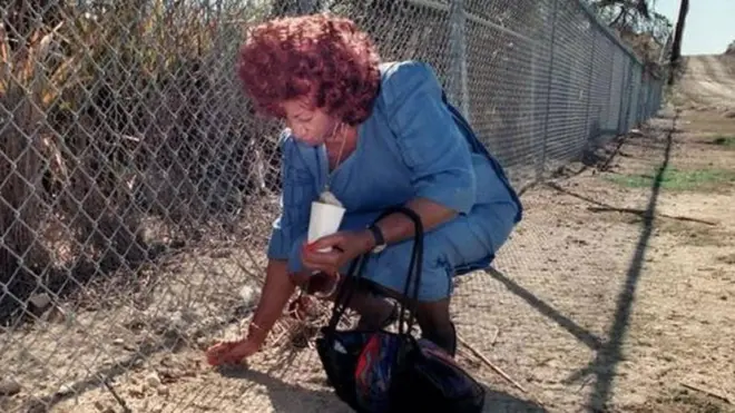 Celia recoge tierra de Cuba a través de la valla de la base de Guantánamo.