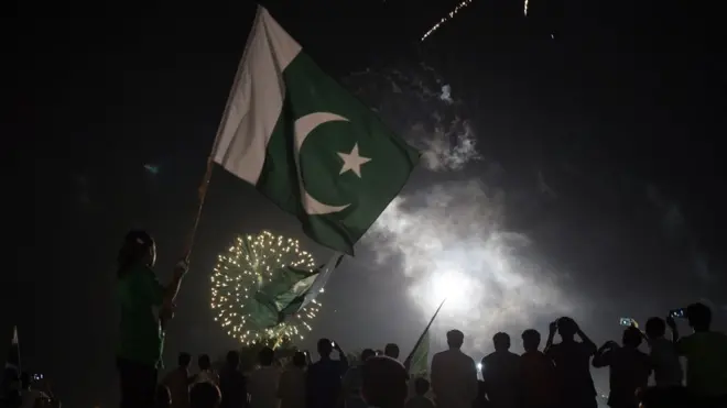 Pakistani residents carry national flags as they watch fireworks in Islamabad on 14 August 2017 to mark Independence Day.
