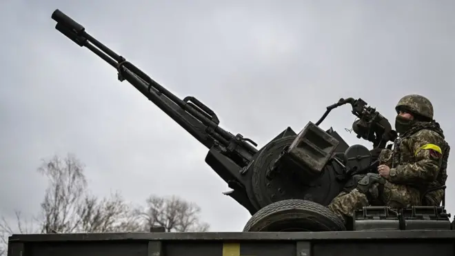 Un soldat ukrainien garde sa position assis sur un canon antiaérien ZU-23-2 sur une ligne de front, au nord-est de Kiev, le 3 mars 2022.