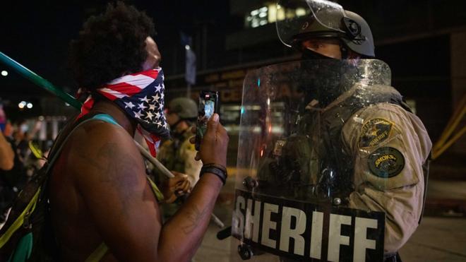美国洛杉矶一场声援威斯康辛州枪击事件伤者的“黑人的命也是命”上一名黑人示威者（左）与一位洛杉矶县警察防暴警员（右）对话）（25/8/2020）