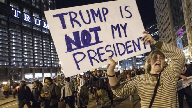 A protester carries a sign reading "Trump is not my president"