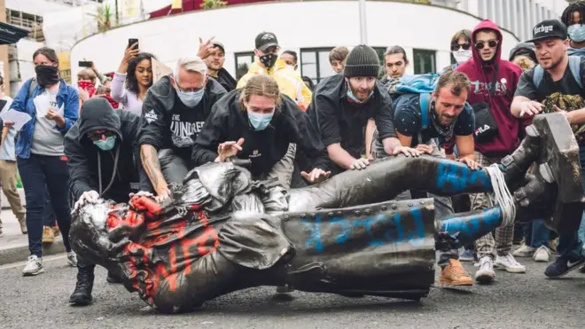 متظاهرون يجرون تمثالا على الأرض