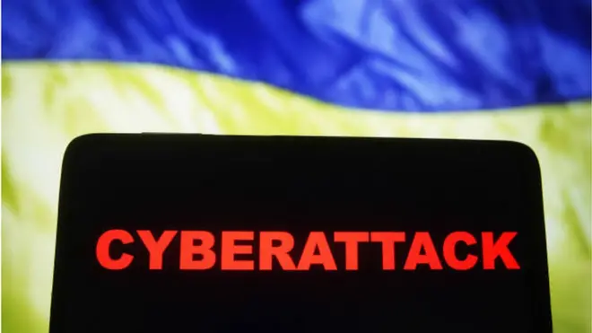 رسم تمثيلي للهجوم السيبراني الذي تعرضت له المؤسسات الأوكرانية يحمل كلمة "هجوم سيبراني بالانجليزية على خلفية العلم الأوكراني.
