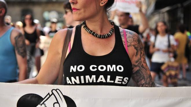 A woman with a banner against bullfighting, while wearing a shirt where you can read "I do not eat animals" - she's marching at a demonstration in Pamplona (N Spain) against animal cruelty on the occasion of the festivities of San Fermin.