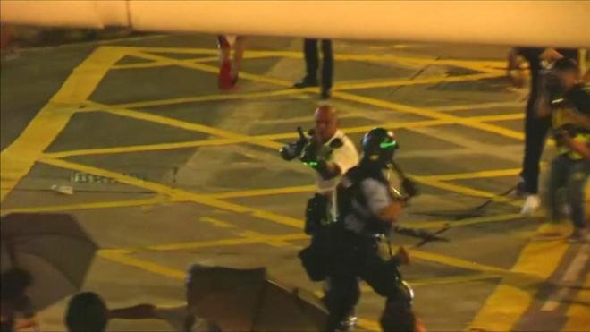 Policeman points gun at protesters in Hong Kong