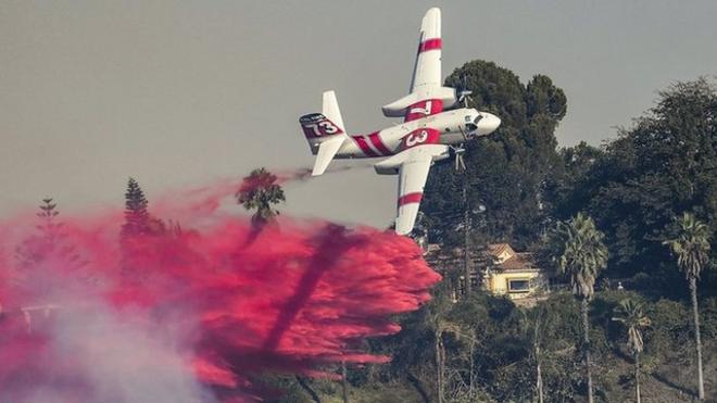 Una avioneta sobrevuela el lujoso barrio de Bel Air, en Los Ángeles, California, para extinguir el incendio Skirball