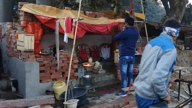 तंबू के नीचे रखी गई प्रतिमाओं के आगे अर्चना करते लोग