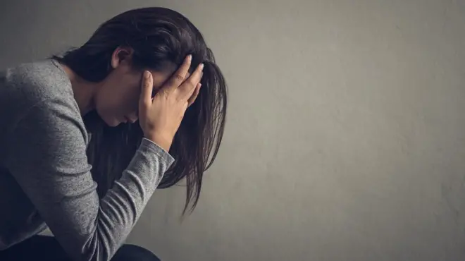 Woman with her head in her hands sitting.