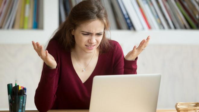 Mujer contrariada viendo una computadora portátil.