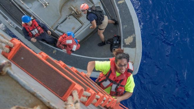 Tasha Fuiaba, uma velejadora dos EUA que navegava há cinco meses em um veleiro danificado, subindo a bordo do USS Ashland no Oceano Pacífico, em 25 de outubro de 2017