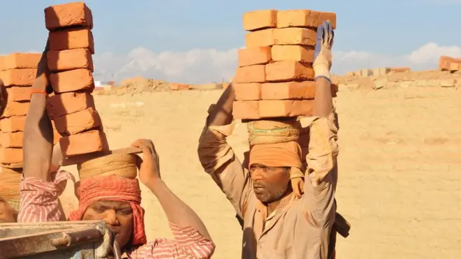 عمال يحملون الطوب