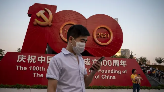 People taking pictures in front of a sign celebrating the 100th anniversary of the founding of the Communist Party of China in Shanghai.