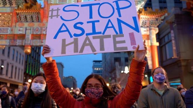 Woman holding sign reading 'stop Asian hate'