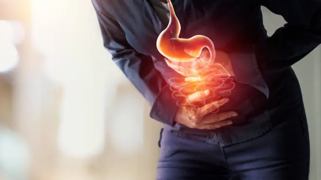 Persona que se toca el estómago con dolor.