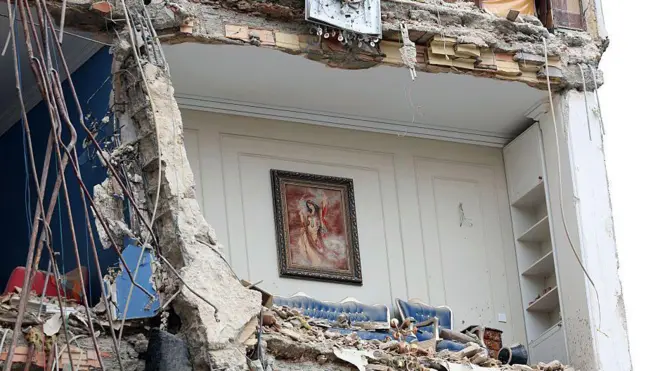 نمایی از اتاقی که یک طرفش فروریخته و در میان خرابه ساختمانی است