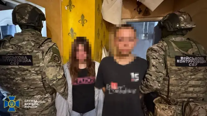 Правоохоронці тримають дівчину і хлопця, їхні обличчя заблюрені 