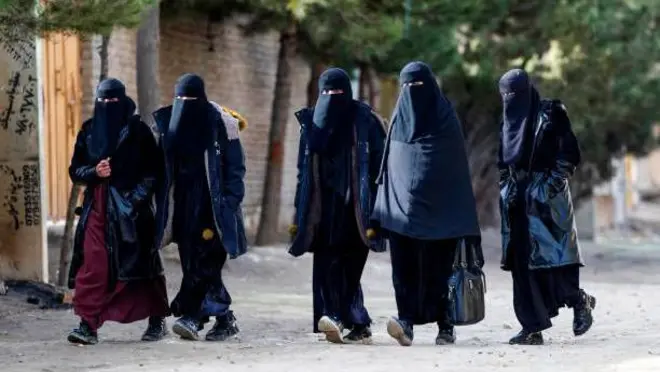تصویر پنج زنی که حجاب‌های سیاه بر تن دارند. این زنان نقاب سیاه نیز پوشیده اند و در جاده‌ای در کنارهم قدم می‌زنند.