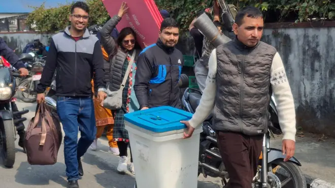 प्रतिनिधिसभा सदस्य निर्वाचनका लागि मतदान सामग्री बुझेर मतदान केन्द्रतर्फ लिएर जाँदै मतदानमा खटिएका कर्मचारी