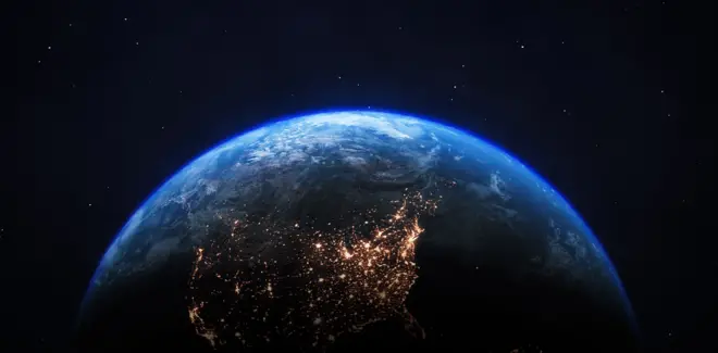 A photo of the upper hemisphere of Earth taken from space, with some of the land masses illuminated by electric lighting 