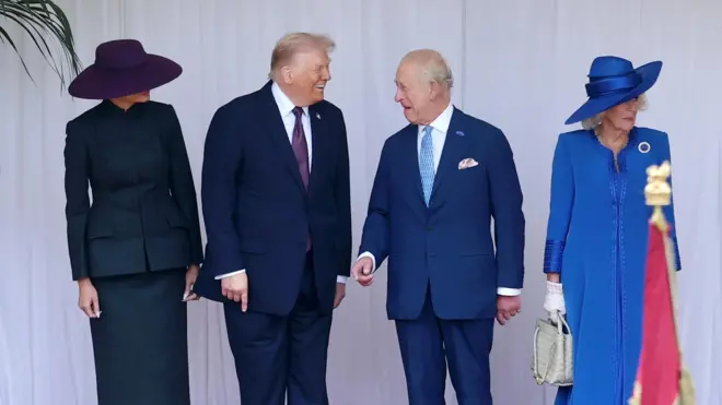 Дональд Трамп и король Карл III смеются. Мелания Трамп смотрит на них, ее лицо не видно под полями шляпы. Королева Камилла смотрит в другую сторону, держа в руке ридикюль