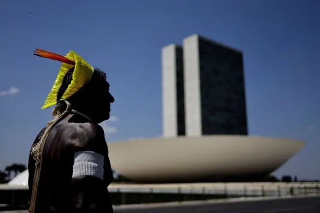 Homem indígena com cocarbet penaltypenasbet penaltyfrente ao prédio do Congresso Nacional 